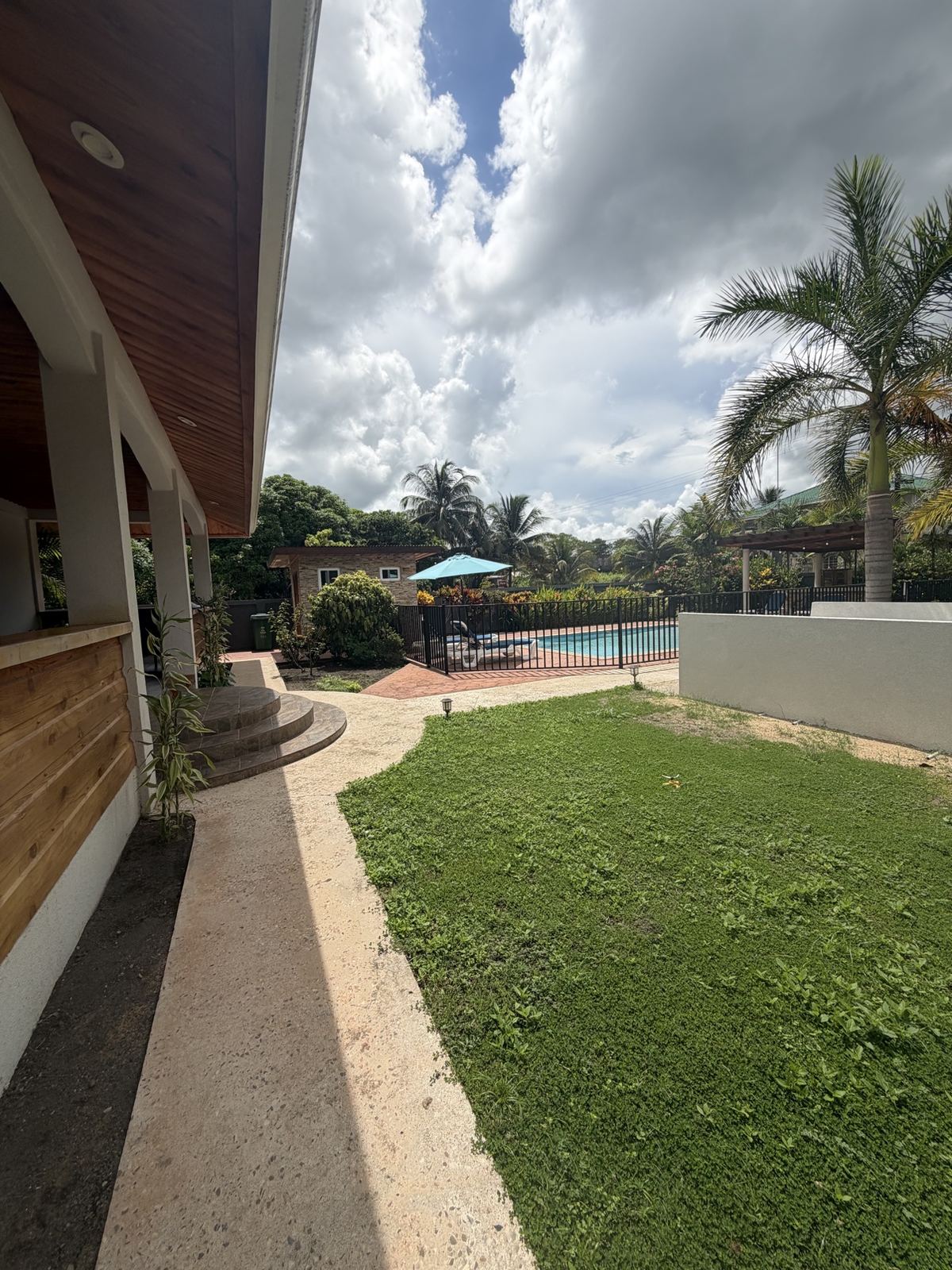 Covered walkway beside the Paradise Palms villa with the lawn and pool in the distance